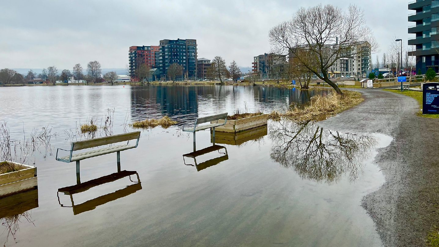 Vy över en grusgång runt munksjön, där sittplatser ligger under vatten som översvämmat från sjön.