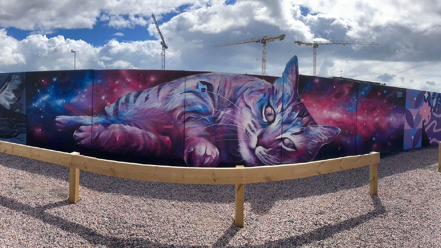 En muralålning på en liggande katt i färger som går i rymdtema: rosa, blå, lila.