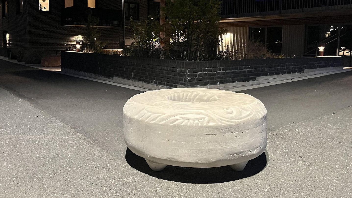 Ett betonghinder i form av en munk (bakverket) med utkarvade mönster på ovansidan