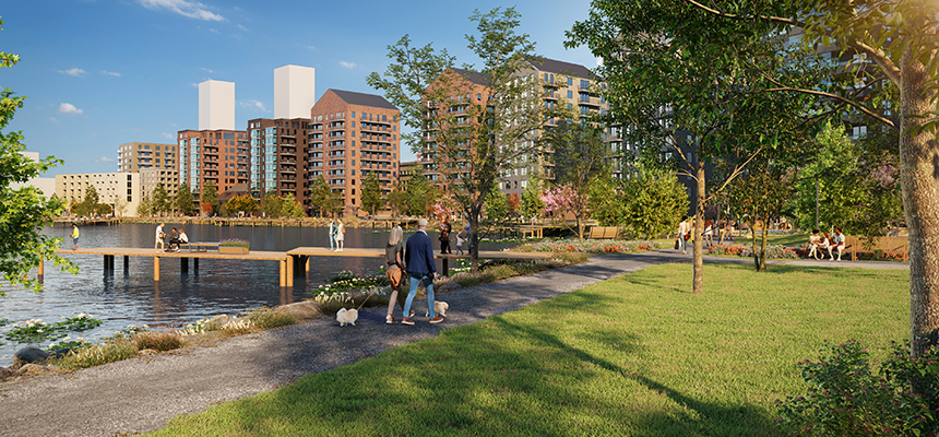 En grönskande park med människor som promenerar längs vattnet. I vattnet syns flertalet bryggor.