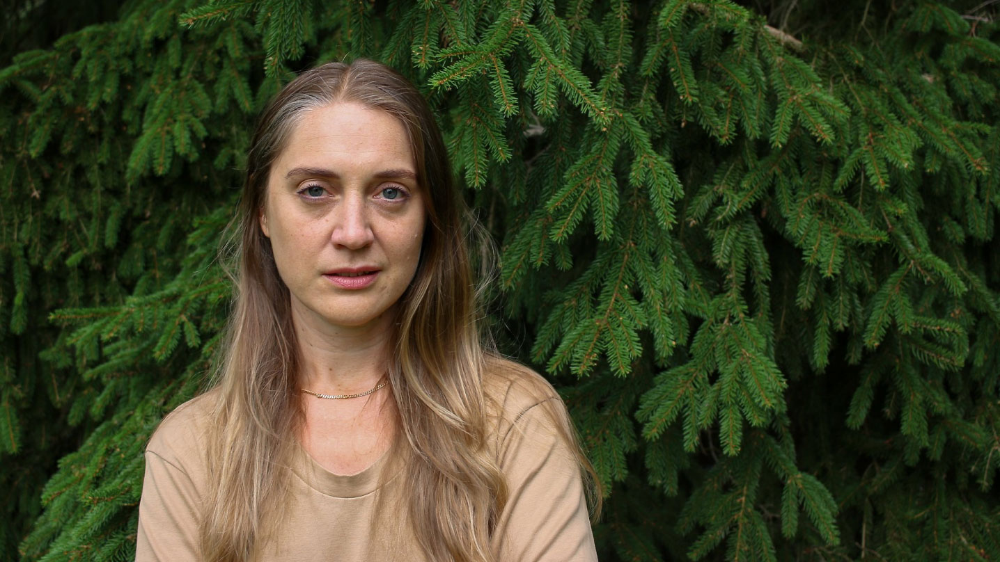 Konstnären Hanna Wildow porträtteras framför en gran.