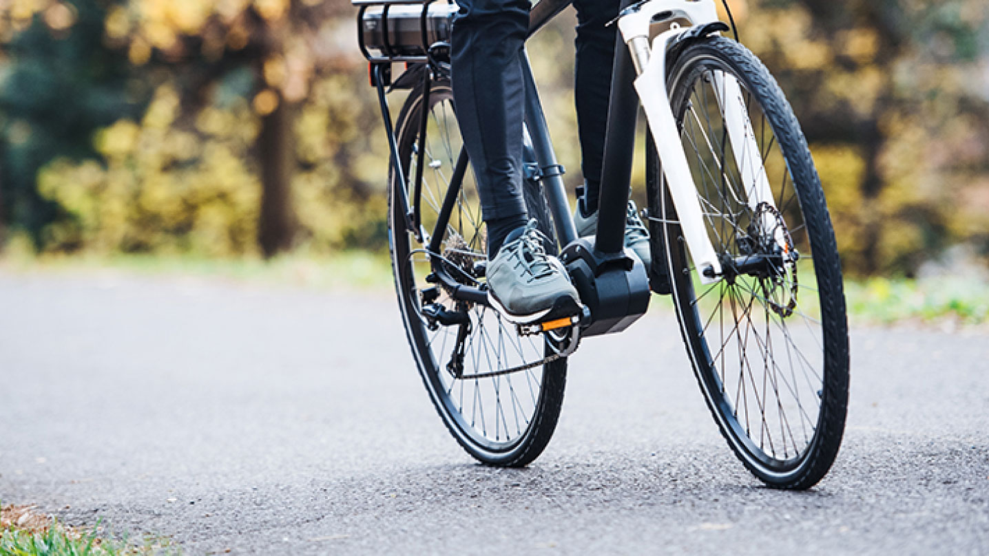 Foto taget på en cyklist i rörelse på cykel på asfalt. Man ser från knäna och neråt.
