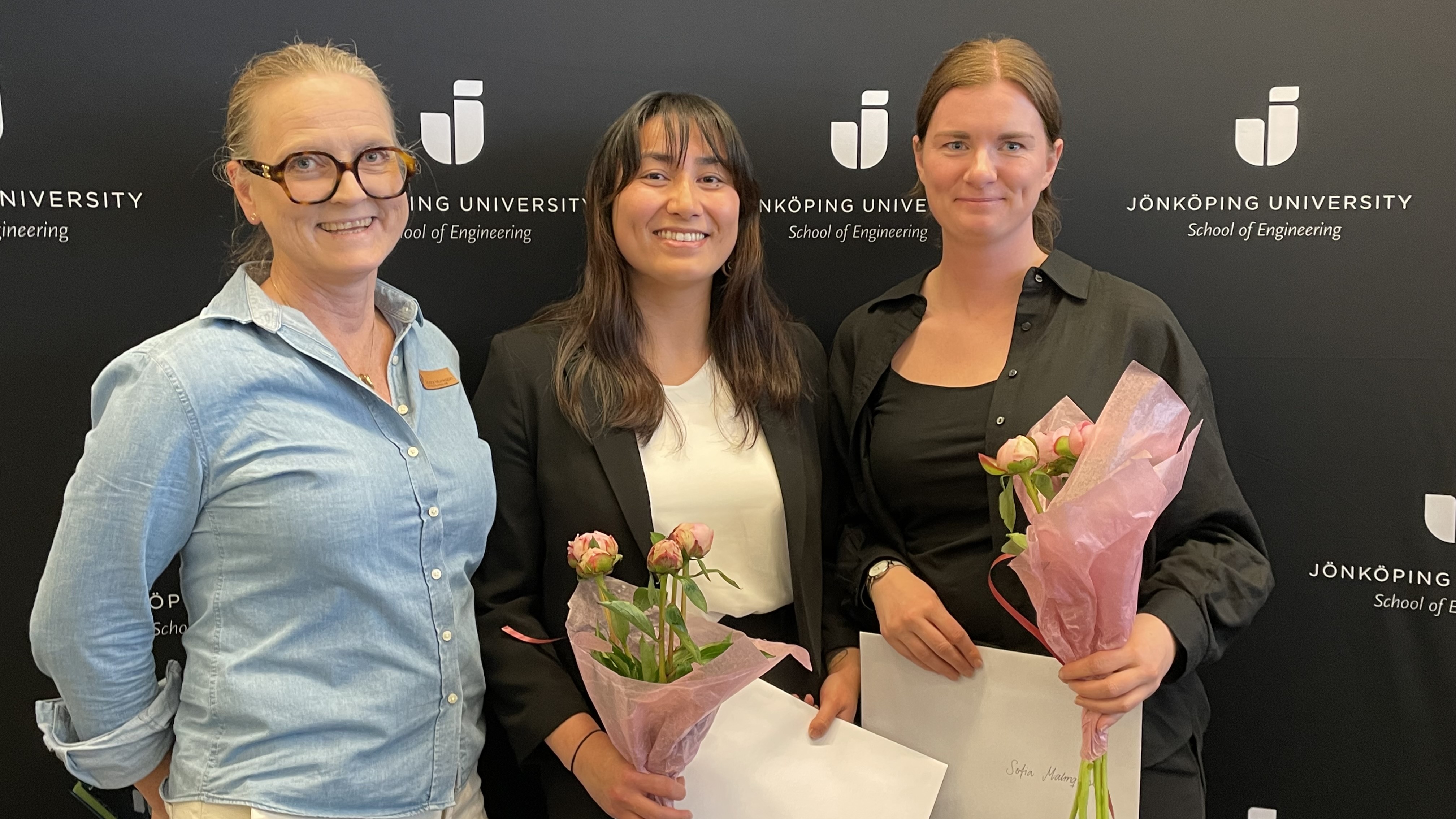 Bild på tre kvinnor. Två av dem håller blommor och diplom i handen.