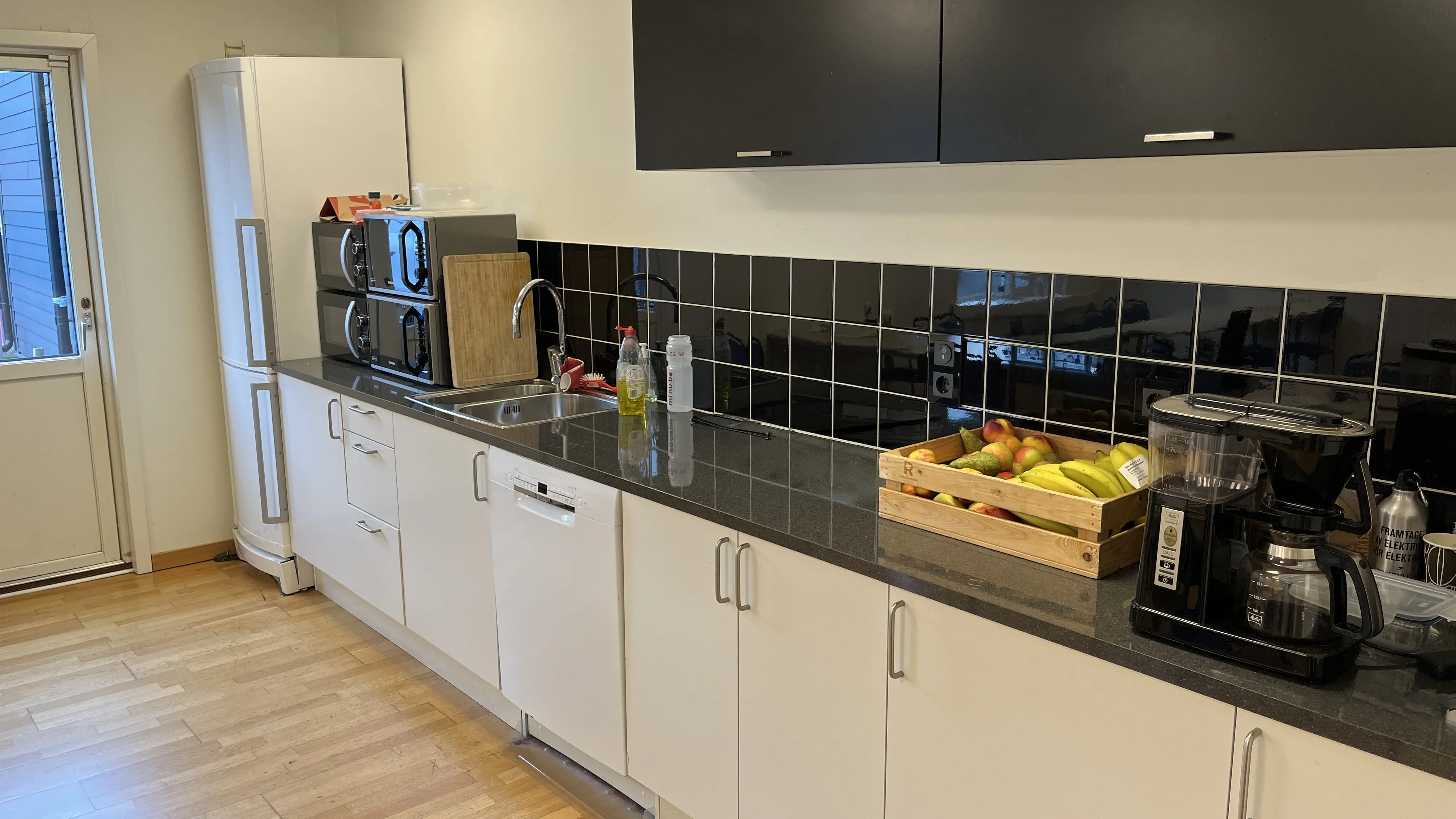 Kök med arbetsbänk, förvaring, kylskåp och diskmaskin.