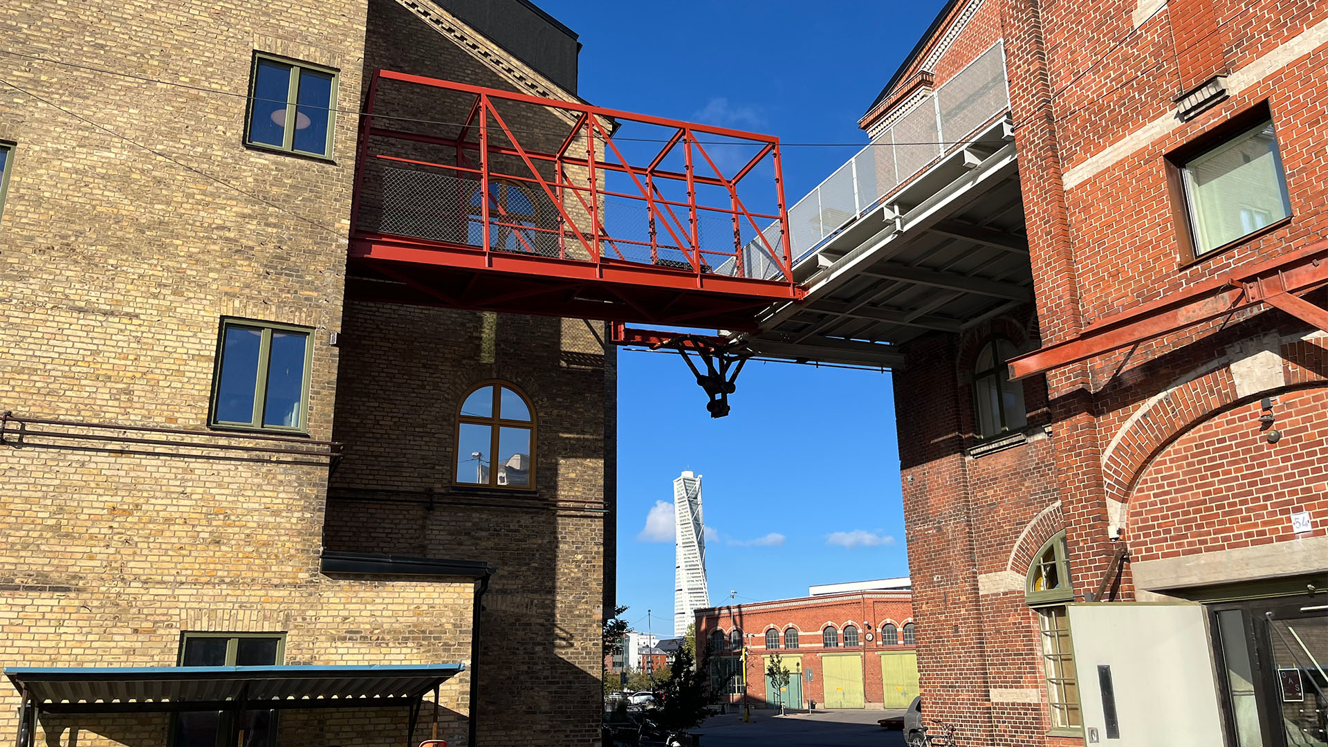Två äldre tegelbyggnader. Mellan byggnaderna syns Turning Torso