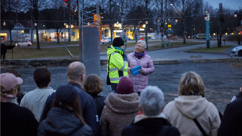 Två personer står med mikrofon och pratar inför en publik som syns i förgrunden.