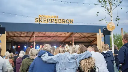 En stor plan grusyta framför tegelhus i olika färger.