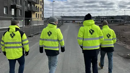 Fyra personer i gula varseljackor går på en väg. 