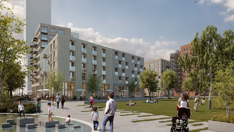 En grön park med människor som rör sig. I bakgrunden syns bostadshus i olika höjder.