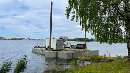 En pråm ligger vid strandkanten av en sjö.