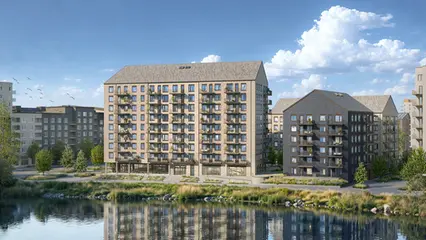 En beige byggnad med balkonger framför en spegelblank sjö. 