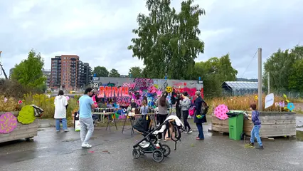 Vuxna och barn står framför en vägg och sprayar graffiti.