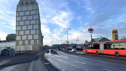 Tvåfilig väg. Till vänster syns ett höghus och till höger en röd buss.