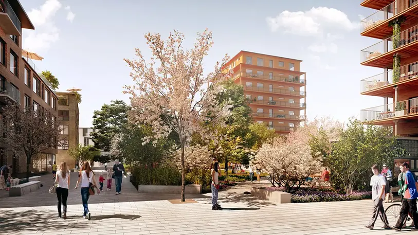 Grönskade park med planteringar och träd. Framför parken syns stenläggning och människor som rör sig. 