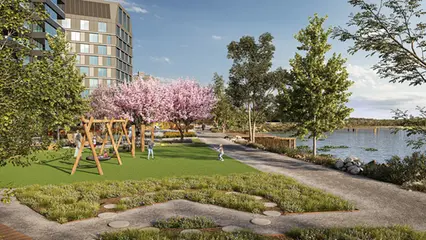 Grön park med träd och planteringar. En sjö syns till höger i bild och en gungställning med lekande barn i mitten.